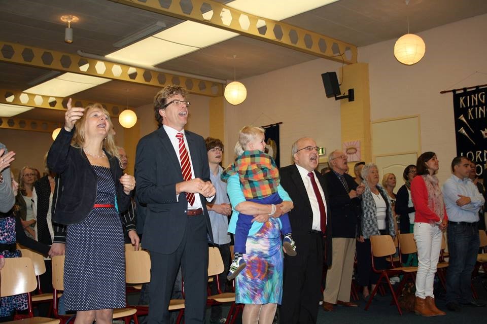 Gemeenteleden staand in aanbidding tijdens een samenkomst