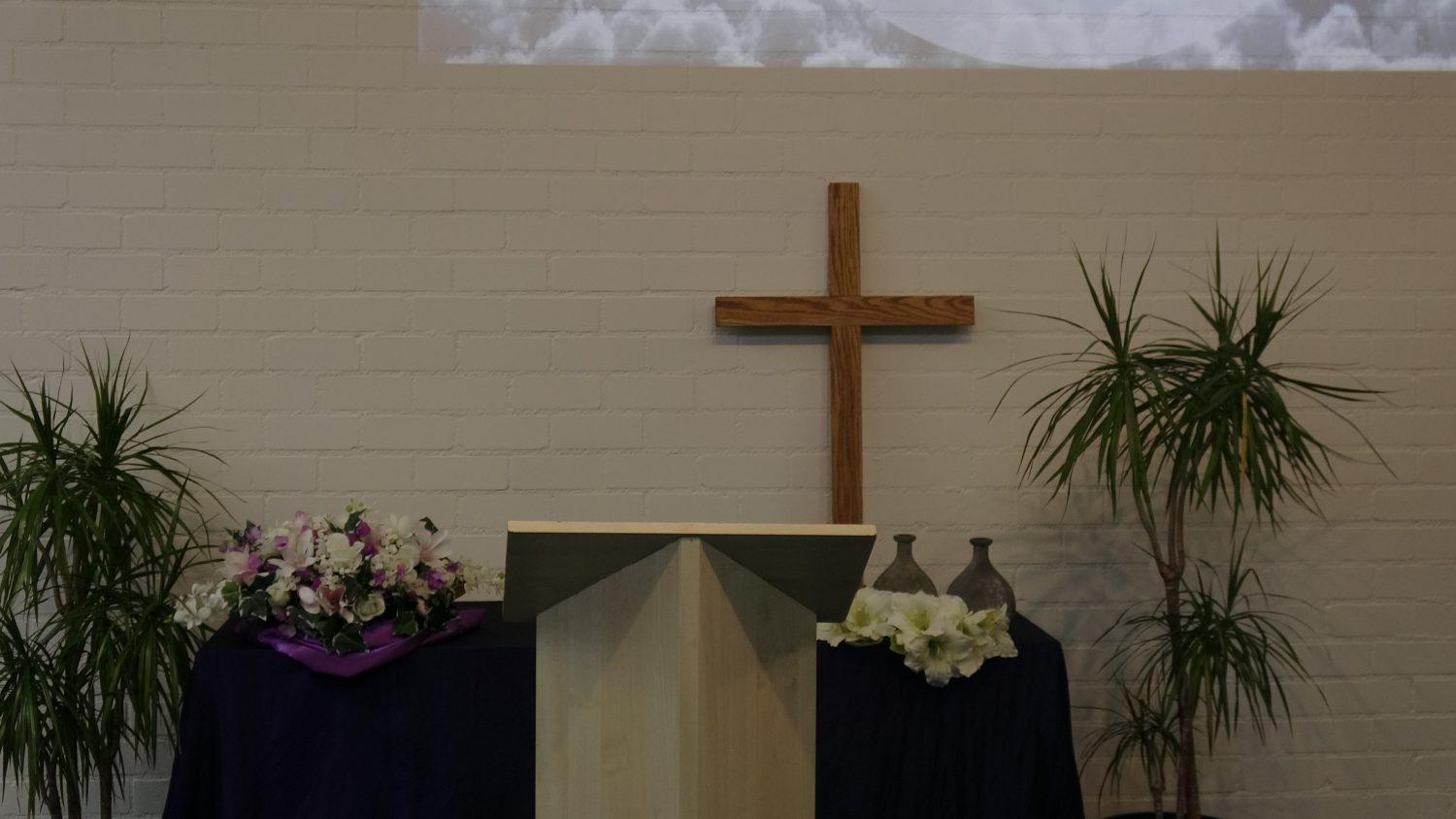 Het podium in de samenkomstzaal van Ichthus met een houten kruis aan de muur